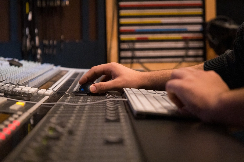 Closeup of a students hands working on the recording studio mixing board.